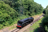 BR Standard Class 9F No 92214 at Birstall passing the tank traps on 25.6.23 with a Loughborough - Leicester North - Loughborough driver experience working