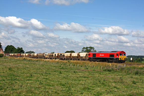 66001 in DB Schenker red is seen at Rearsby Foot crossing heading towards Melton Mowbray  on 9.7.14 with 6L43 0925 Mountsorrel Sdgs - Kennett Redland Siding loaded 4 wheeled hoppers