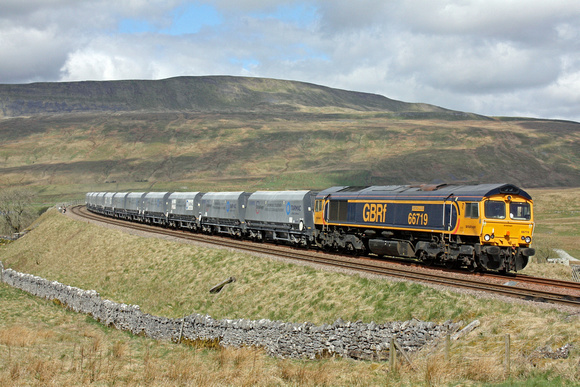 GBRf 66719 'Metro-land' is seen in the lovely Yorkshire Dales countryside at Ribblehead on 28.4.17 with 6M37 1112 Arcow Quarry  - Pendleton (Brndle Hth) loaded stone hoppers