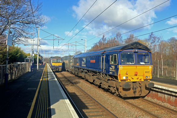 DRS 66421 at Coatbridge Central Station on 22.2.23 with 4D01 1151 Blackford Freight Terminal to Mossend Down Yard Highland Spring Bottled water train. ScotRail 320321 waits with 2C30 1130 Dalmuir to C