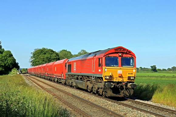 DB Cargo Class 66 No 66069 in red livery passes East Goscote on 14.6.23 with 4Z71 1506 Ely Mlf Papworth Sidings to Arpley Sidings loaded sand red DB hoppers