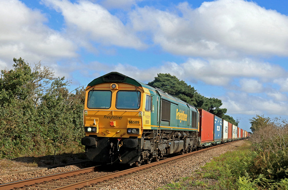 Freightliner Class 66 No 66589 powers towards Levington Foot Crossing on 17.8.23 with 4M89 1613 Felixstowe North F.L.T. to Ditton (Oconnor) Fliner Intermodal