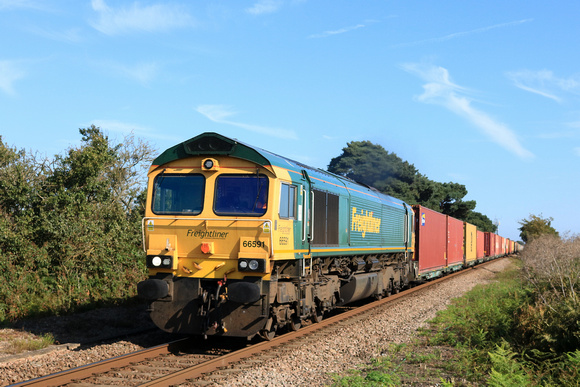 Freightliner Class 66 No 66591 approaches Levington Foot Crossing on 21.8.23 with 4E56 1528 Felixstowe North F.L.T. to Doncaster Ept (F'liners) Intermodal