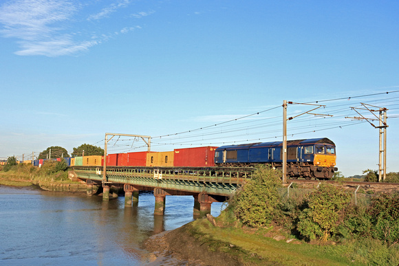 GBRf Class 66 No 66303 formerly DRS with no current branding crosses Cattawade Bridge, Brantham over River Stour on 21.8.23 with  4M02 1738 Felixstowe North Gbrf to Hams Hall Gbrf Intermodal