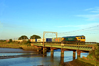 Freightliner Class 66 No 66504 in Powerhaul livery crosses Cattawade Bridge over River Stour in low sun on 21.8.23 with 4M89 1613 Felixstowe North F.L.T. to Ditton (Oconnor) Fliner  after recessing at