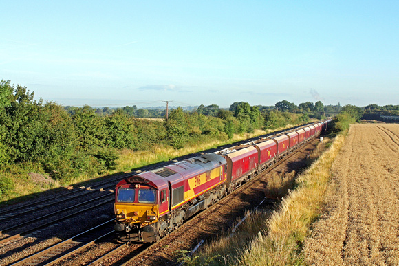 In early morning sunlight DB Cargo 66113 passes Cossington, MML on 10.8.17 heading for Syston East Junction with 6L75 0415 Peak Forest Cemex Sdgs - Ely Mlf Papworth Sidings loaded aggregate hoppers