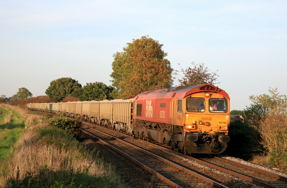 Biffa liveried GBRf Class 66 No 66783 'The Flying Dustman' approaches Langham Crossing on 9.10.23 in low early autumn sun with 6F78 1644 Mountsorell Gbrf to Wellingborough Up Tc Gbrf loaded stone box