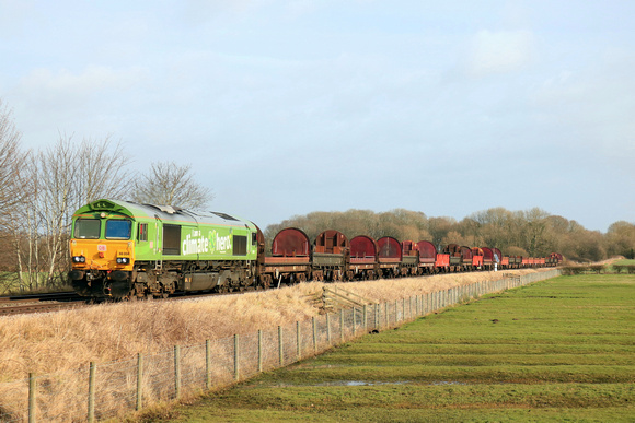 DB Cargo 66004 in special  green “I am a Climate Hero” livery passes Rearsby heading towards Syston East Junction on 24.1.24 with 6V92 1032 Corby B.S.C. to Margam T.C. empty steel coil mounts and wago