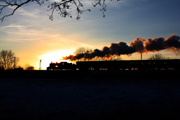 LMS Ivatt Class 2 2-6-0 No 46521 is silhouetted against  the setting sun at a snowy Quorn on 29.12.14 with 1515 Loughborough - Leicester North GCR Christmas Holiday Service